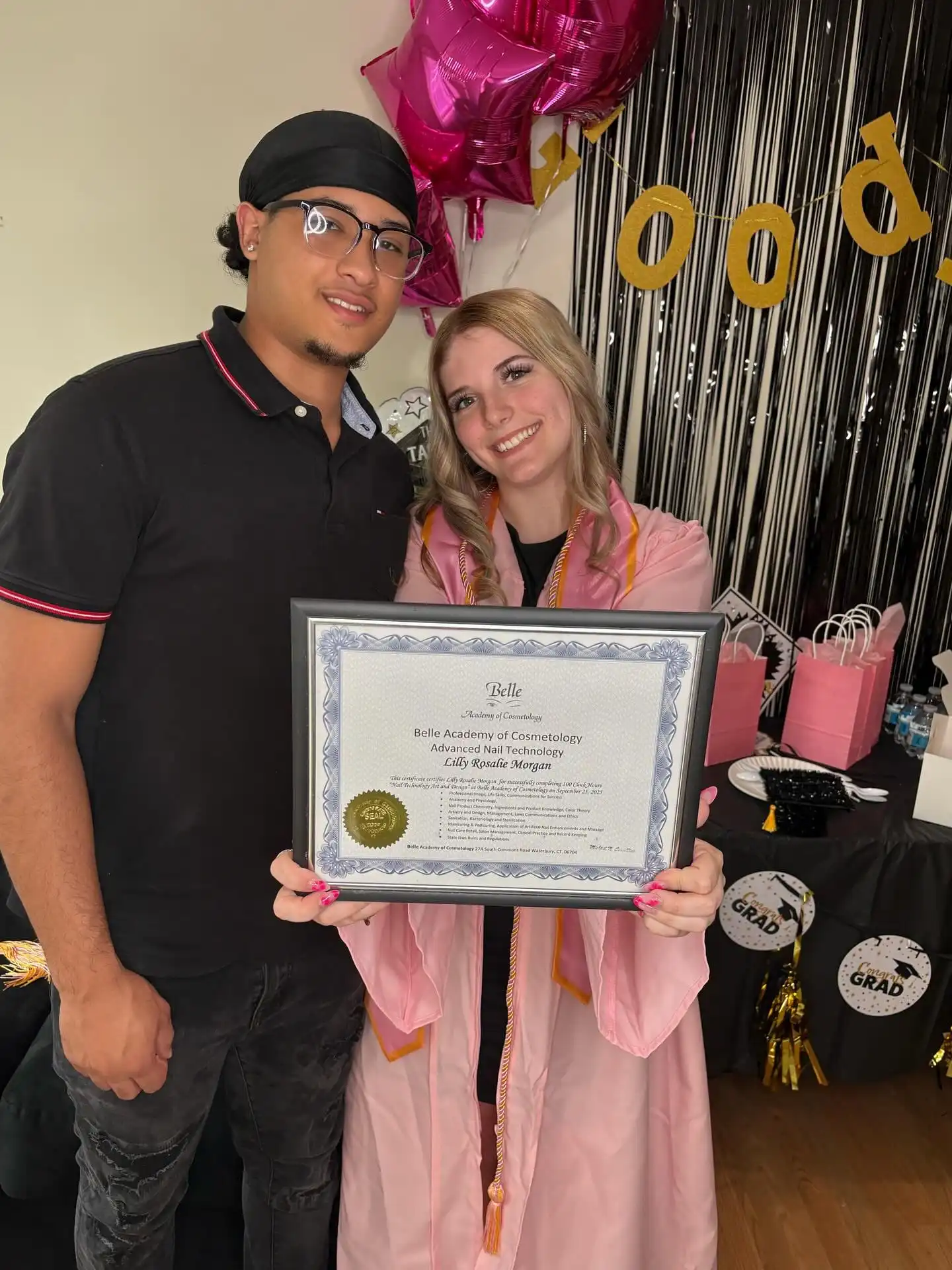 Belle Academy graduate holding diploma with instructor
