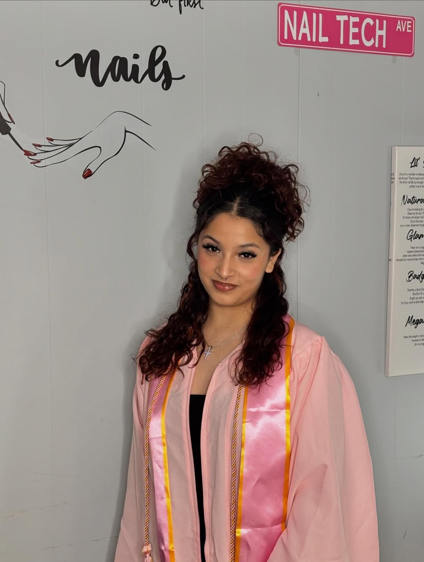 Nail tech graduate portrait in front of Belle Academy wall