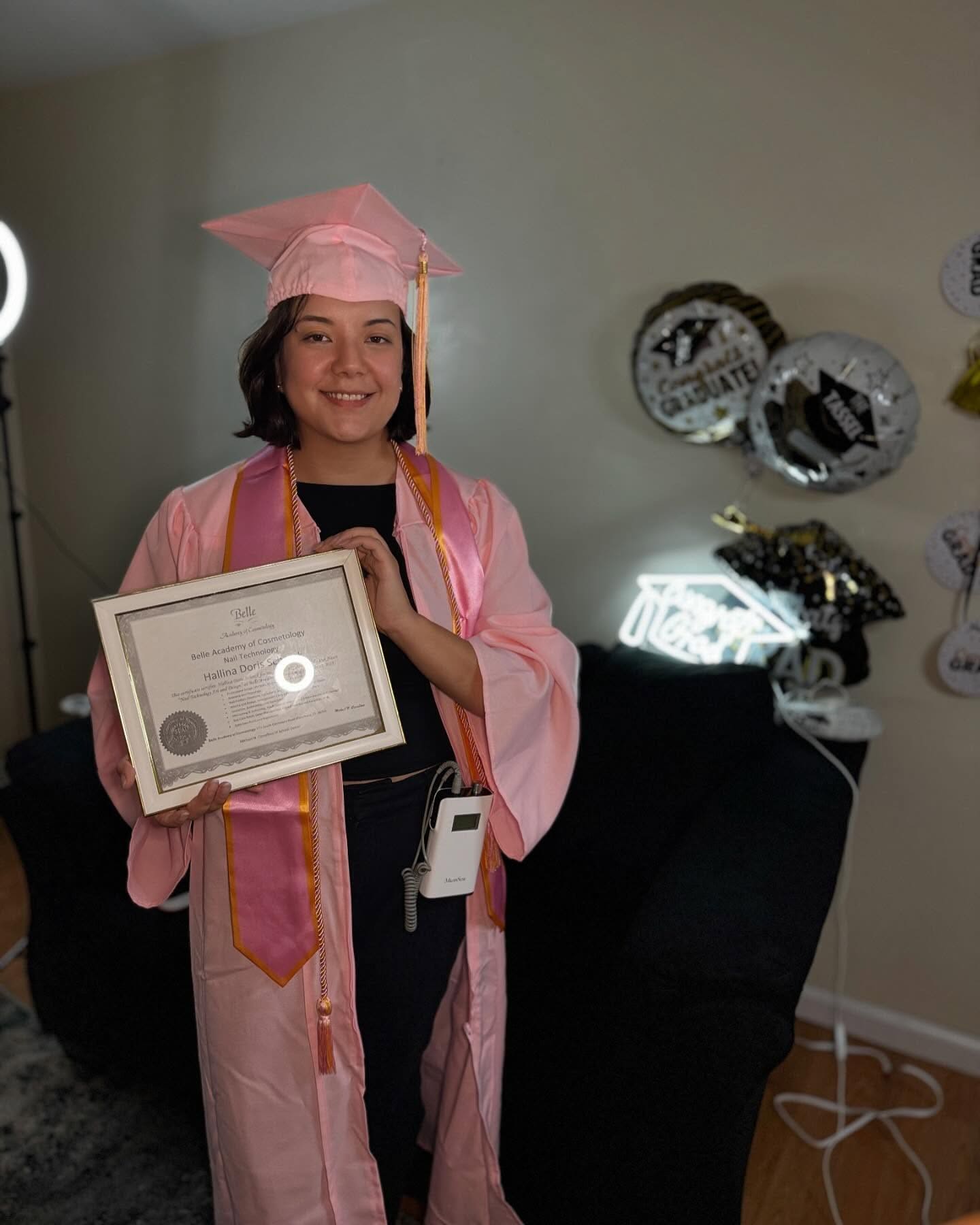 Graduate in pink gown holding Belle Academy certificate