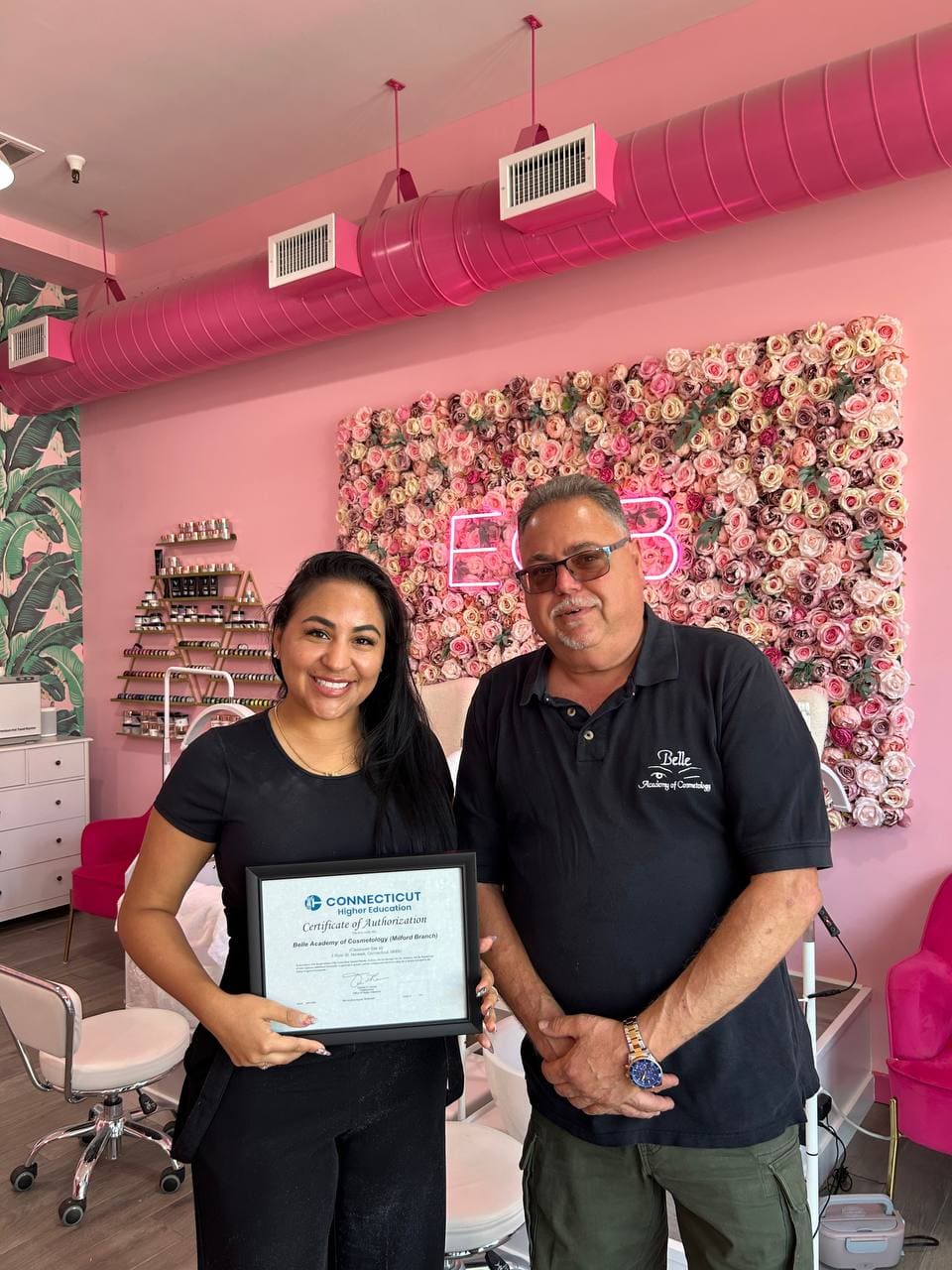Graduate with instructor at pink salon Belle Academy